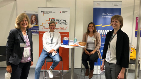 Vier Frauen vor einer Plakatwand