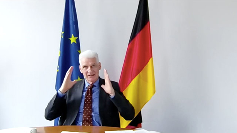 Ein Mann sitzt vor einer EU- und Deutschlandfahne