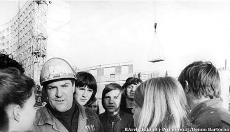 Bauarbeiter umringt von jungen Menschen in den 70er-Jahren